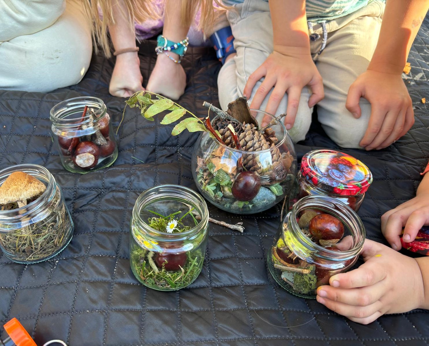 Gläser mit Naturmaterialien und Kinderhände